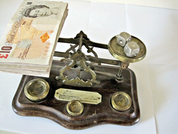 Money and dice on scales
