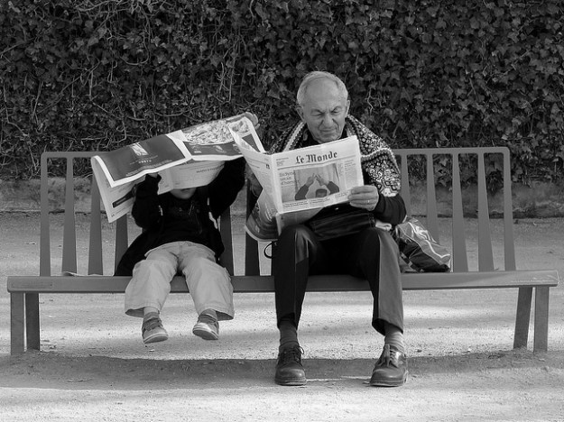 Old man and young boy reading on bench